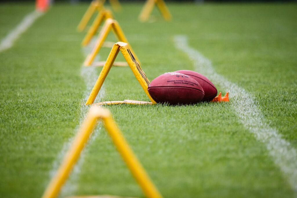 Close-up of an American football on a sports field with yellow training equipment.